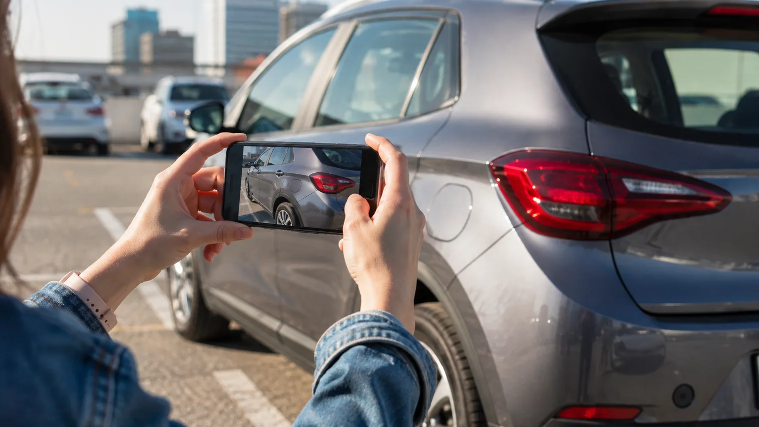 Persona fotografiando con el celular el estado de un auto de renta